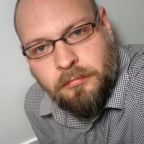 Biggs Thorarensen, a full-bearded white male with glasses wearing a black and white checkered striped shirt.